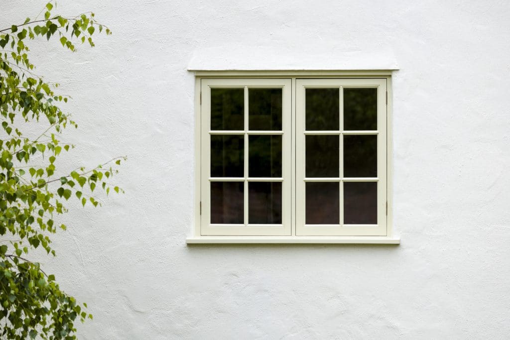 UK house exterior with wooden casement window and white wall rendering