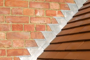 Closeup of new plain red clay tiles and lead flashing on a pitched roof